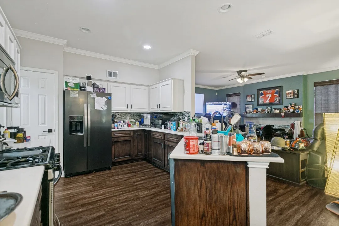 Kitchen featuring wood-finish flooring, two-tone cabinetry with upper white cabinets and lower dark wood-finish cabinets, and a kitchen island with a white countertop