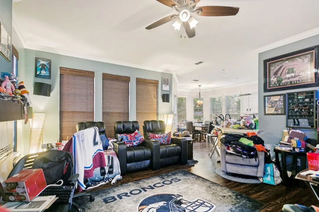 Open-concept living area featuring wood-finish flooring, a ceiling fan, and crown molding