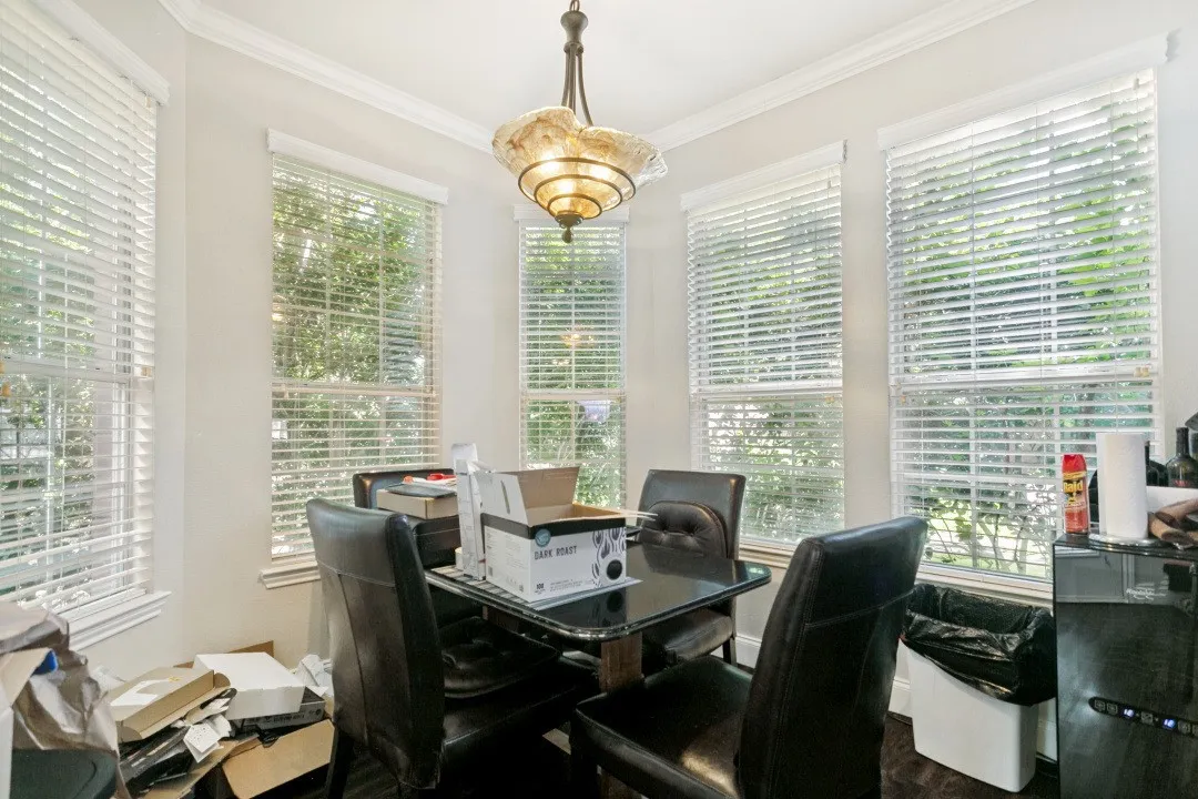 Bay window area featuring five vertical windows with blinds, a multi-tiered chandelier, crown molding, and light-toned wall paint