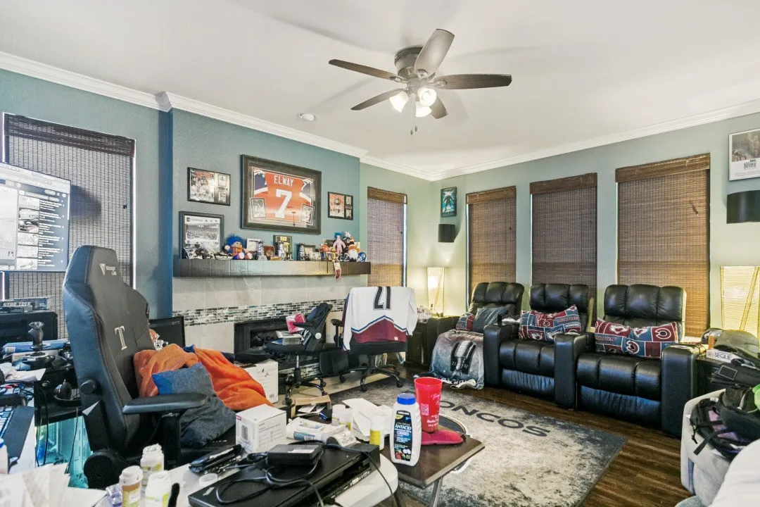 Living space featuring a built-in fireplace with a tile surround and mantel, wood-finish flooring, and crown molding