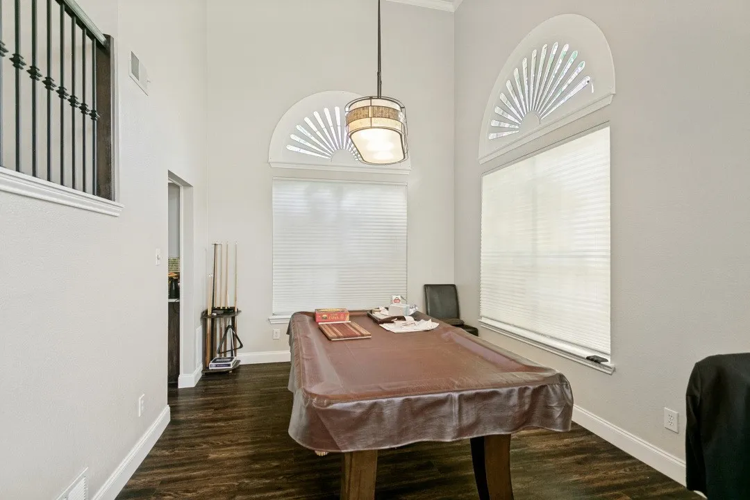 Room featuring high ceilings, two arched transom windows, wood-finish flooring, and white baseboards