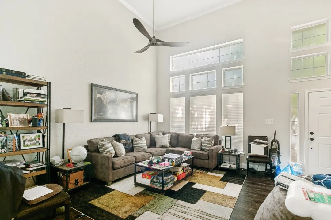 Living room with high vaulted ceilings, dark wood-finish flooring, and multiple windows