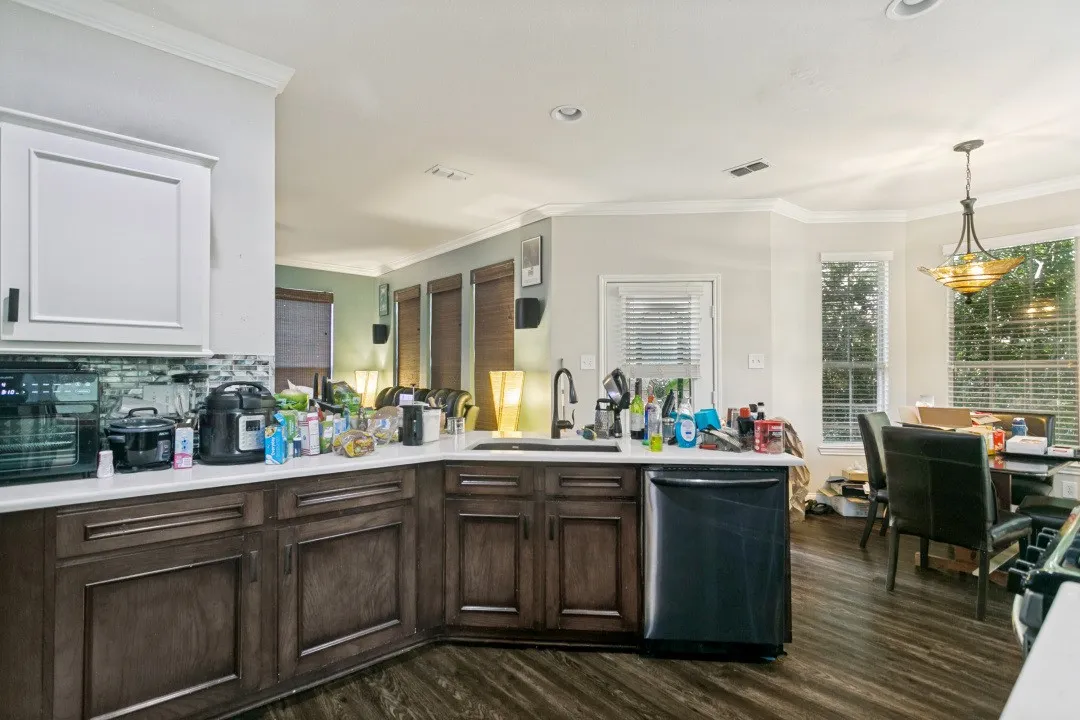 Modern kitchen featuring white upper cabinetry, dark wood-finish lower cabinetry, and a light-colored countertop