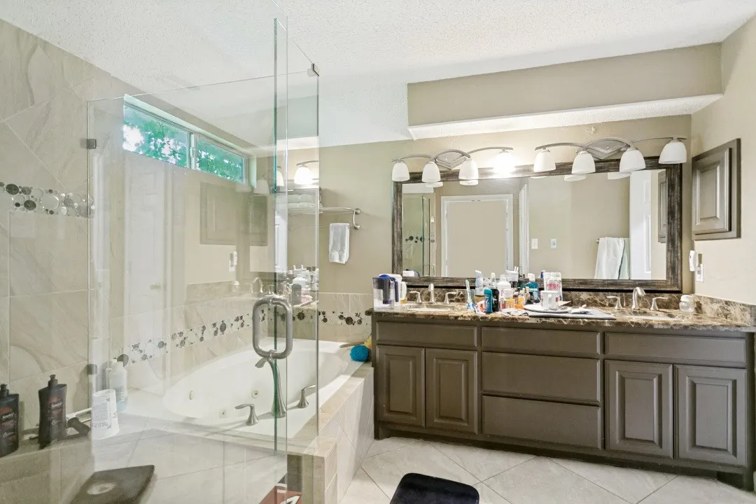 Expansive bath featuring a glass-enclosed shower, built-in jetted tub, dual vanity with undermount sinks, and a large wall-mounted mirror