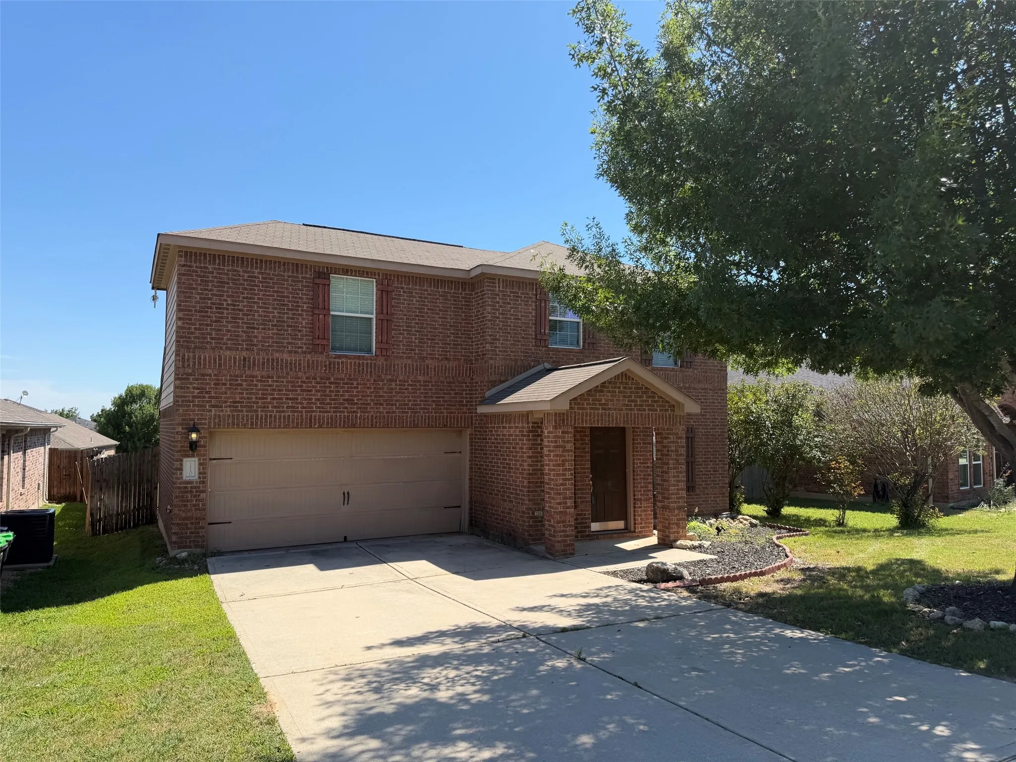 Two-story brick exterior featuring an attached two-car garage, covered entry, and a paved driveway