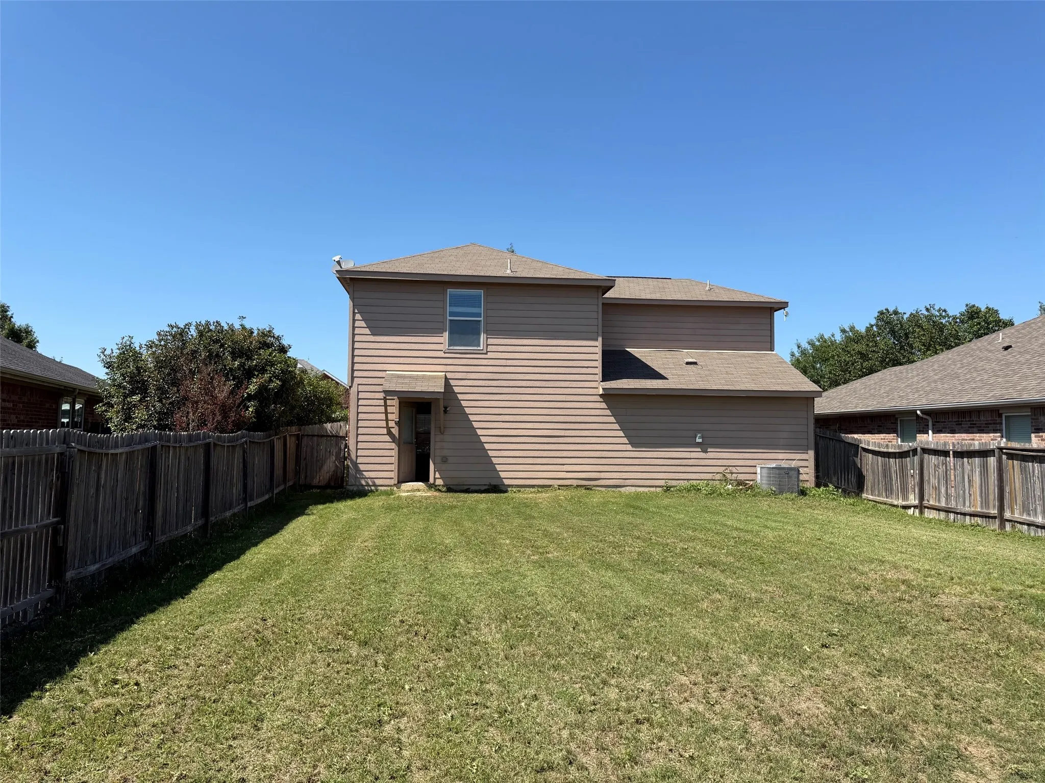 Spacious backyard featuring a large grassy area, privacy fencing, and exterior access to the residence