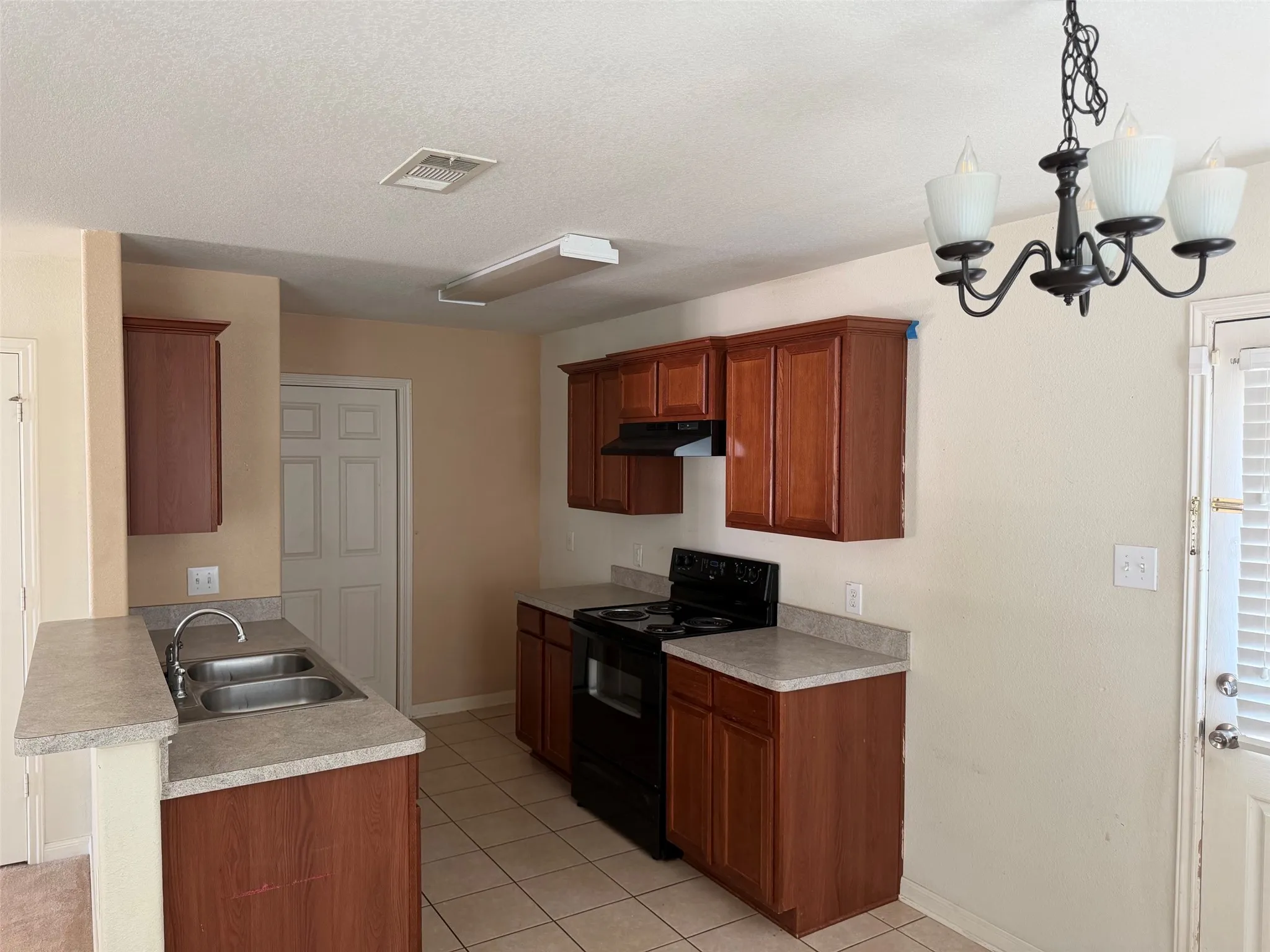 Kitchen featuring wood-finish cabinetry, laminate countertops, and a double basin sink