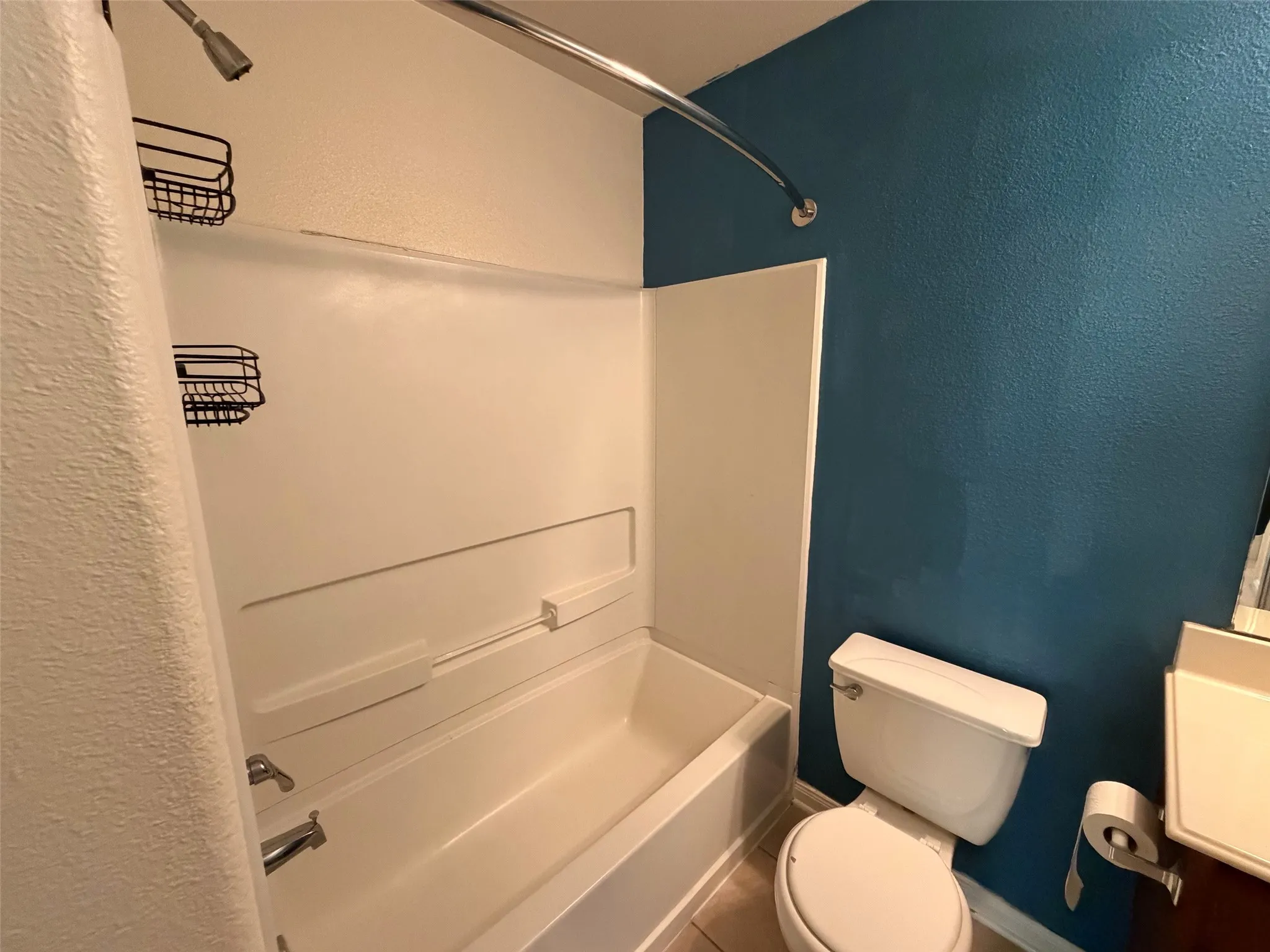 Bathroom featuring a white tub and shower combination with chrome fixtures, a white toilet, and a light-colored vanity with an integrated sink