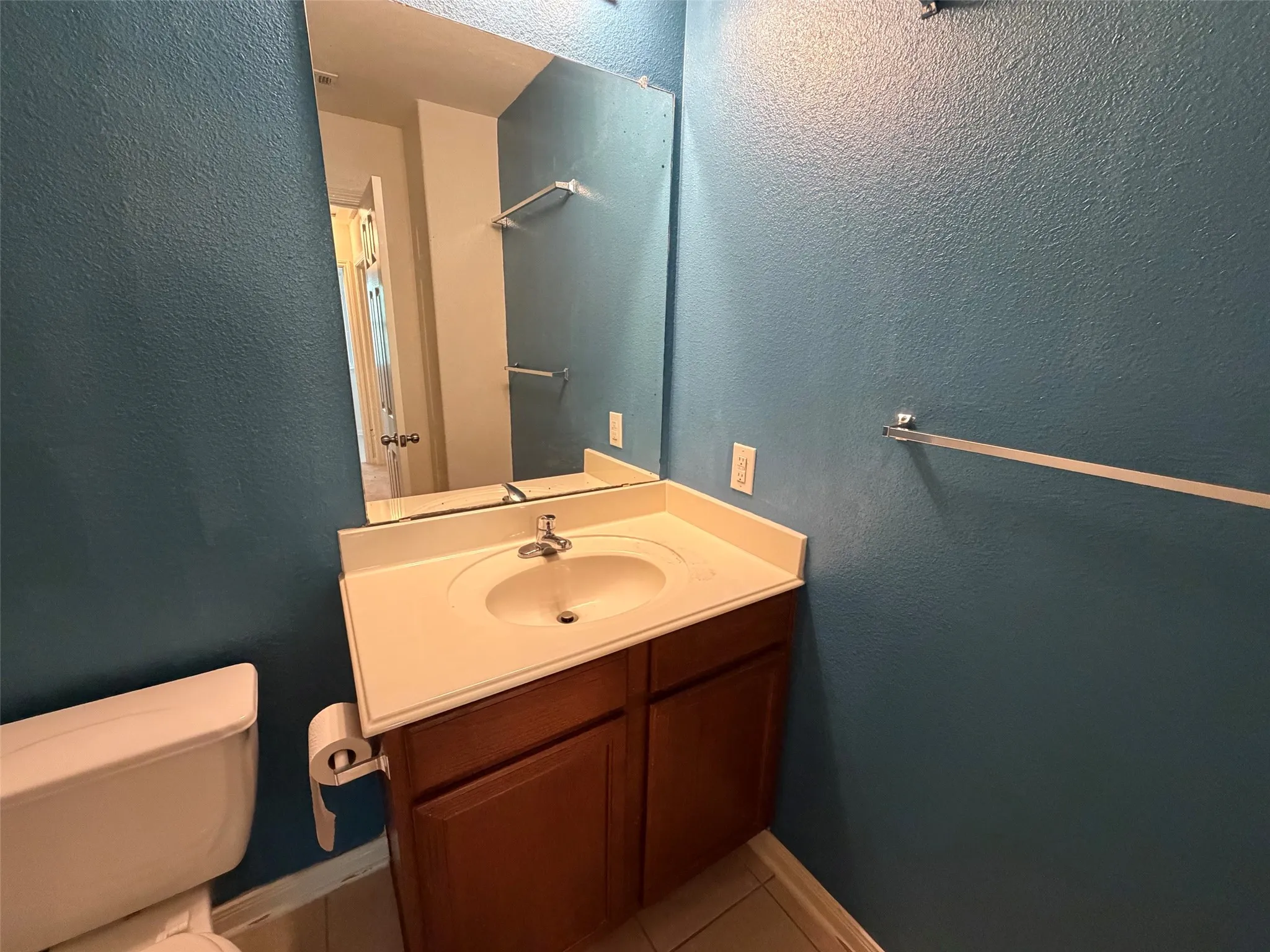 Bathroom vanity with a white countertop and integrated sink, complemented by a wood-finish cabinet