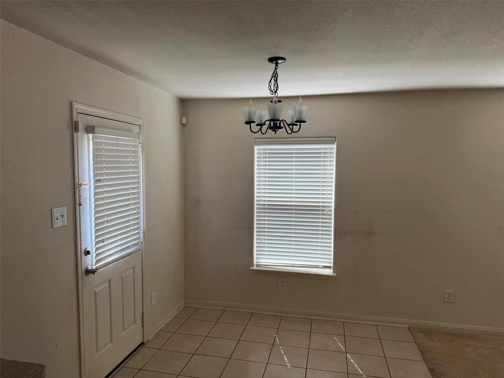 Dining area featuring a chandelier, a window with blinds, and tile flooring