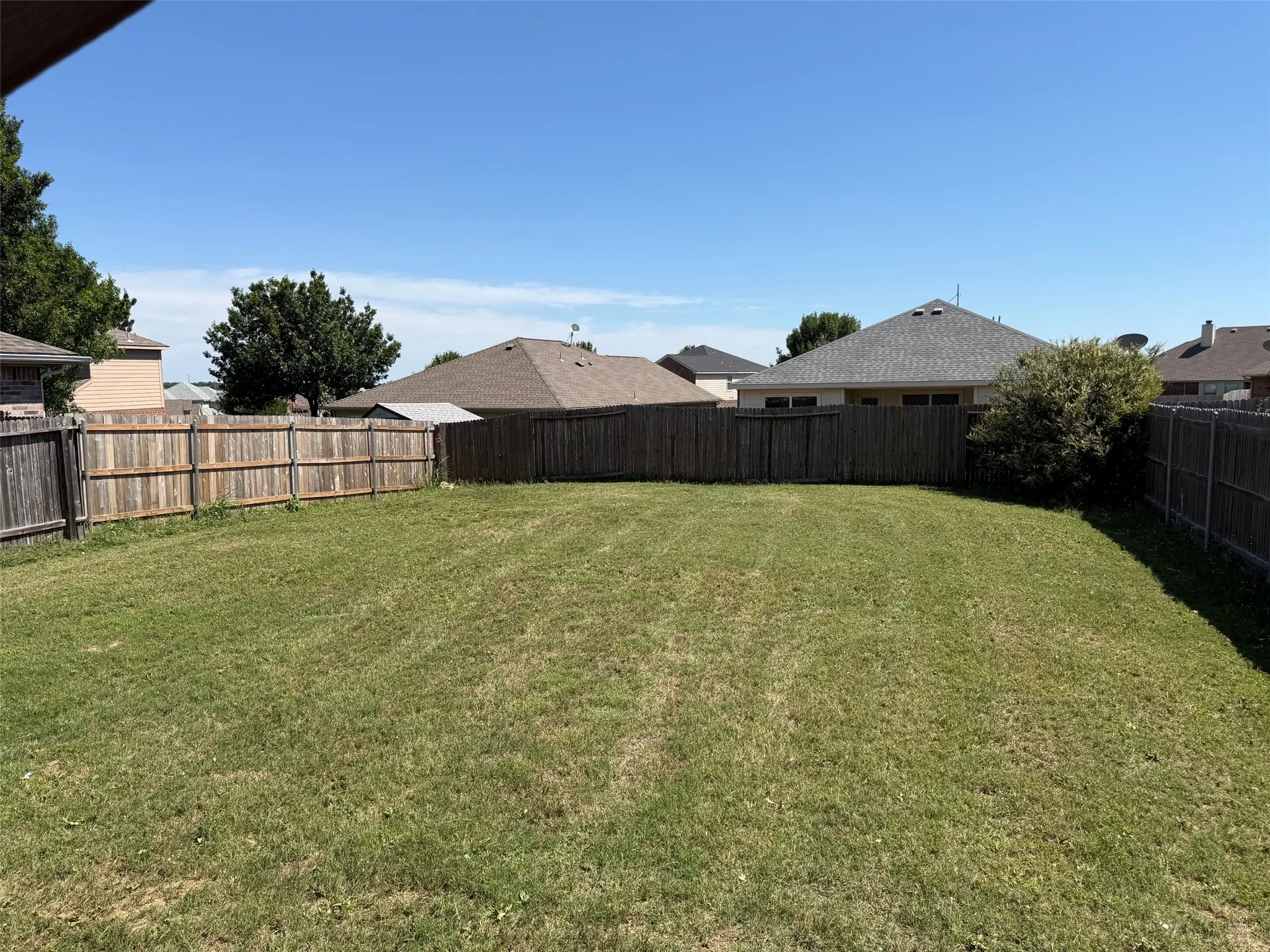Expansive green lawn surrounded by a privacy fence