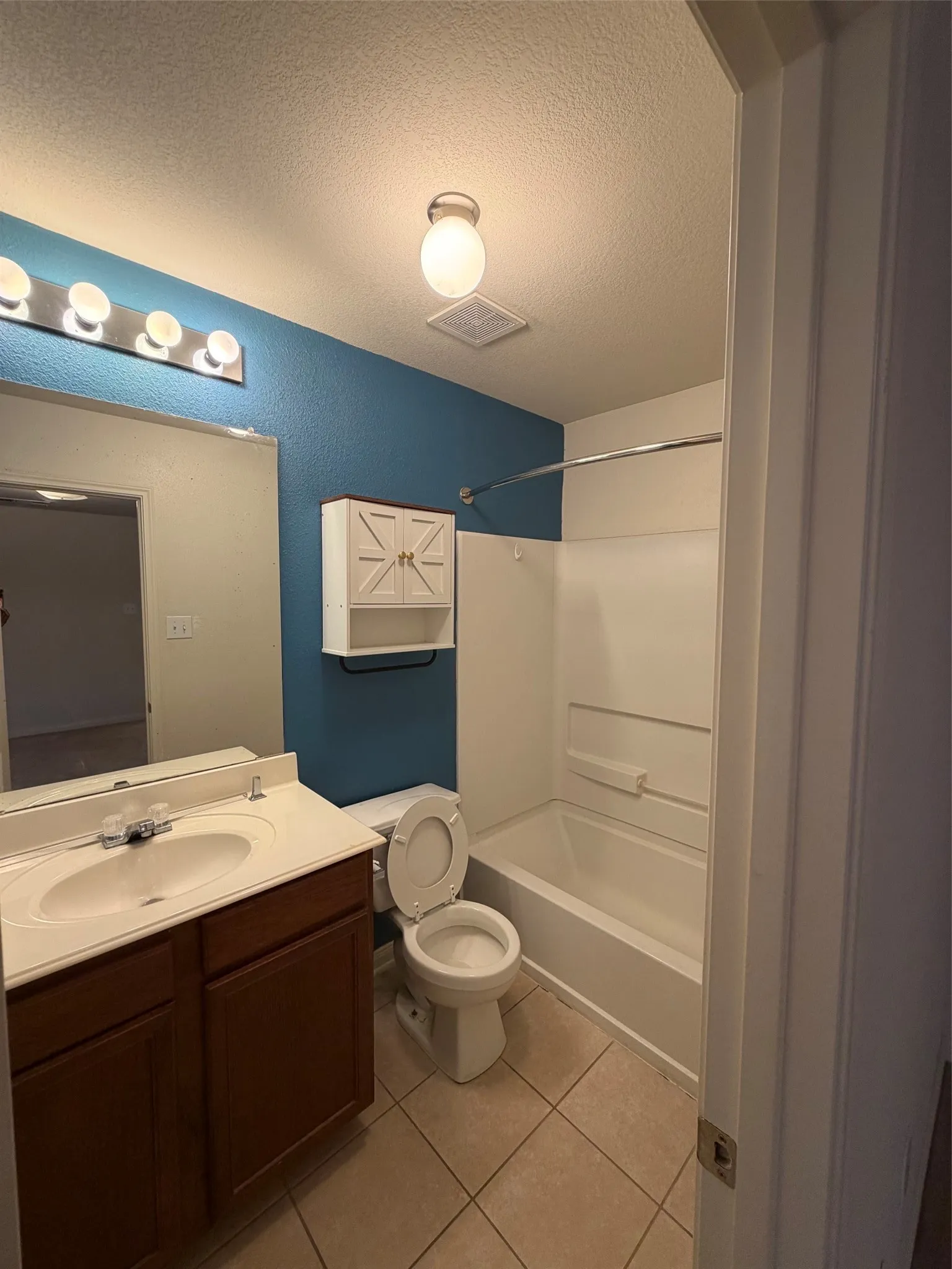 Bathroom featuring a single vanity with a white countertop and wood-finish cabinetry