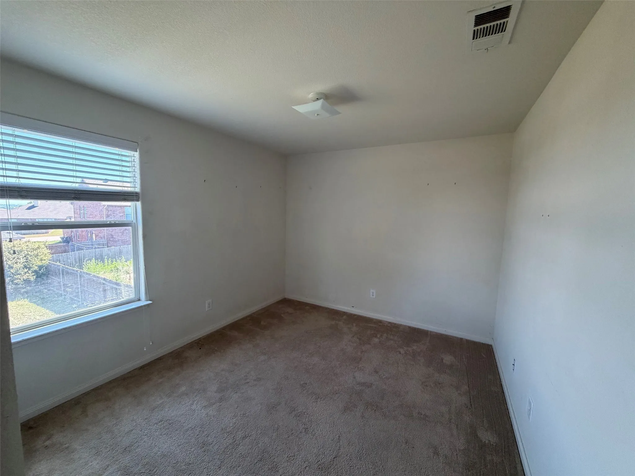Room featuring a window with blinds, carpet flooring, a ceiling-mounted light fixture, and a ceiling vent