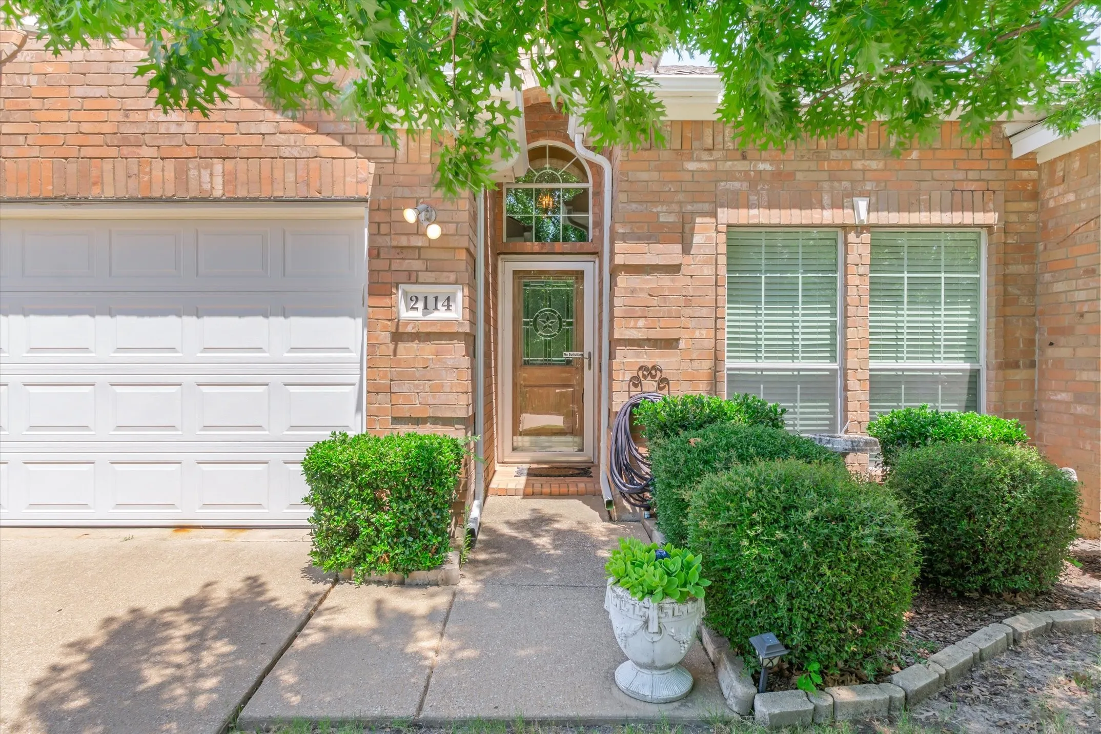 Brick exterior featuring a paneled garage door and a glass-paneled front entry door with an arched transom