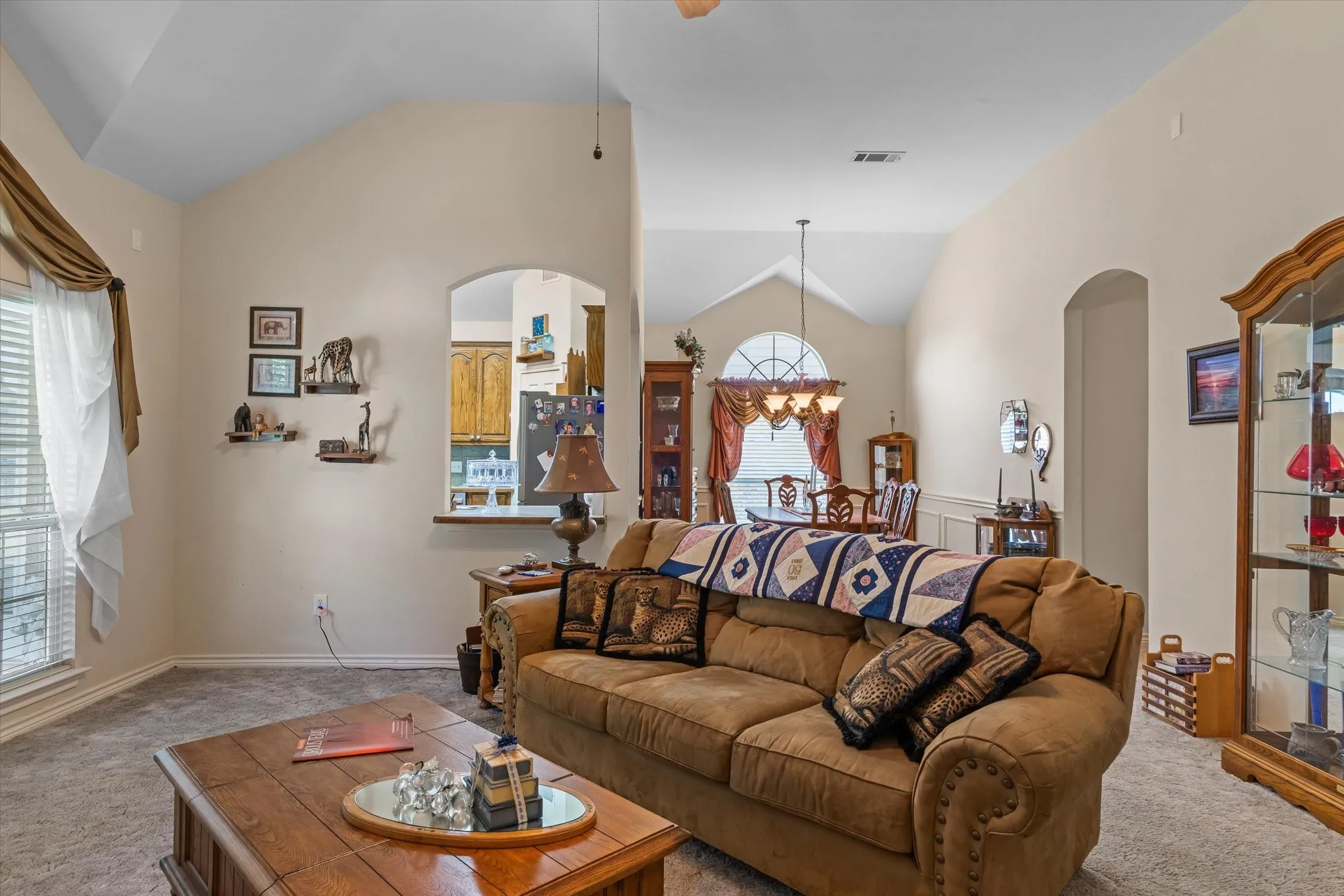 Vaulted ceilings highlight the living area, featuring carpet flooring and neutral wall tones