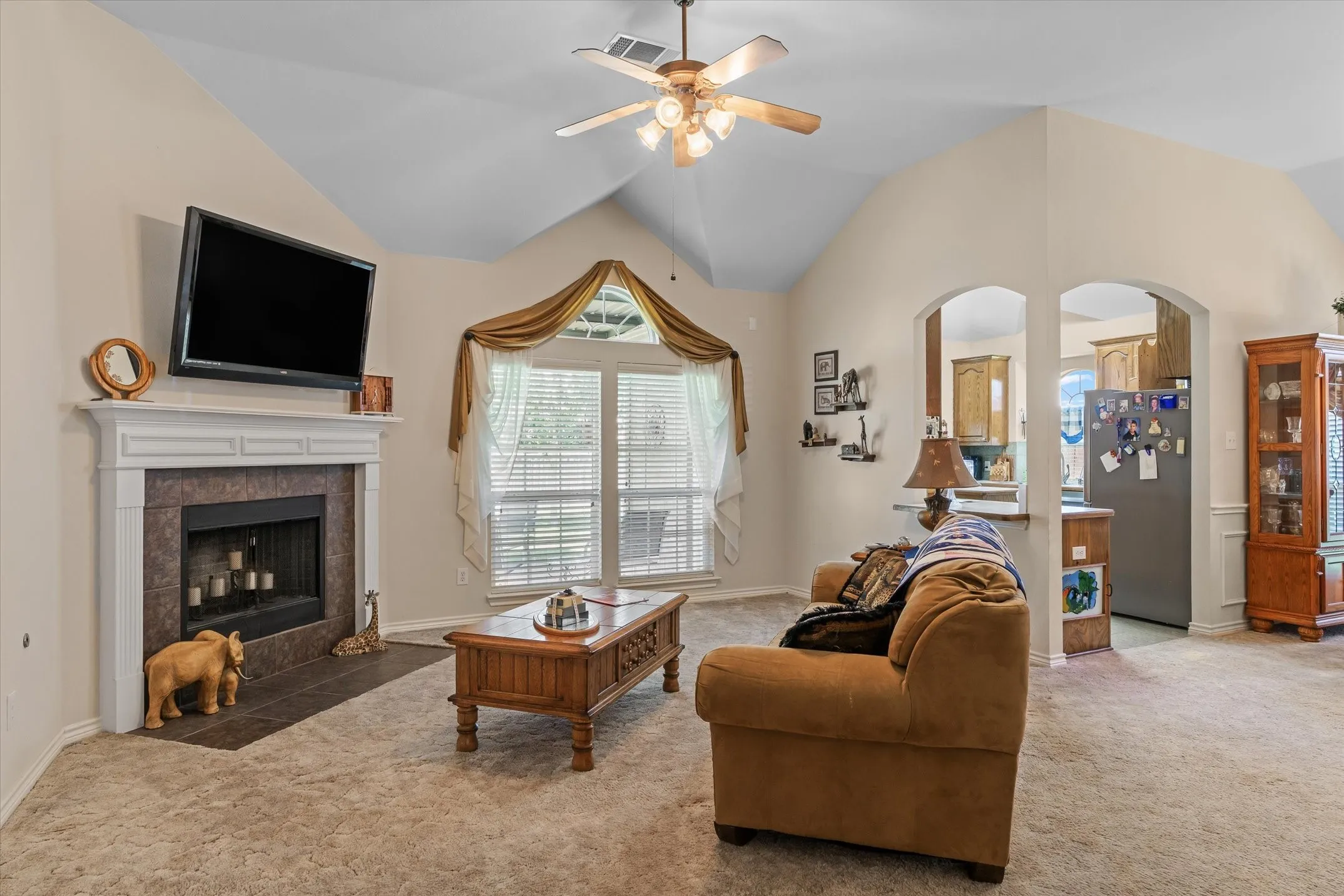 Living area with a vaulted ceiling, ceiling fan, and carpeted flooring