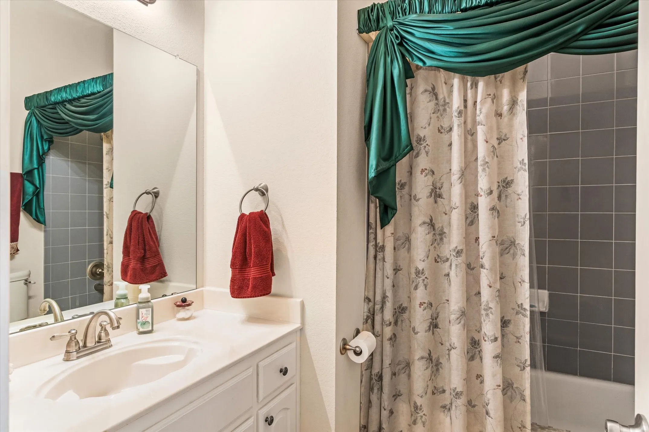 Bathroom featuring a vanity with an integrated sink, brushed nickel faucet, and white cabinetry