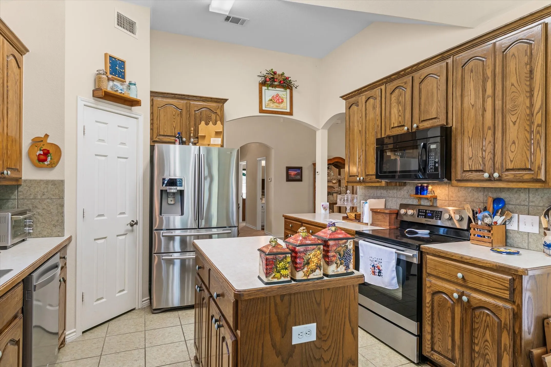 Kitchen featuring wood cabinetry, stainless steel appliances, a center island with countertop, and tile flooring