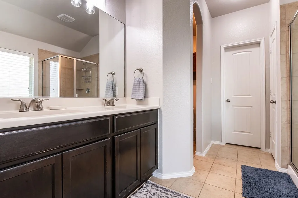 Dual vanity with white undermount sinks, bronze finish hardware, and dark wood cabinetry