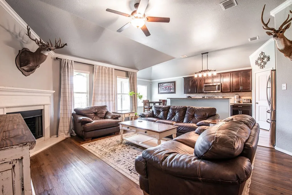 Living area with wood-finish flooring, vaulted ceiling, and ceiling fan
