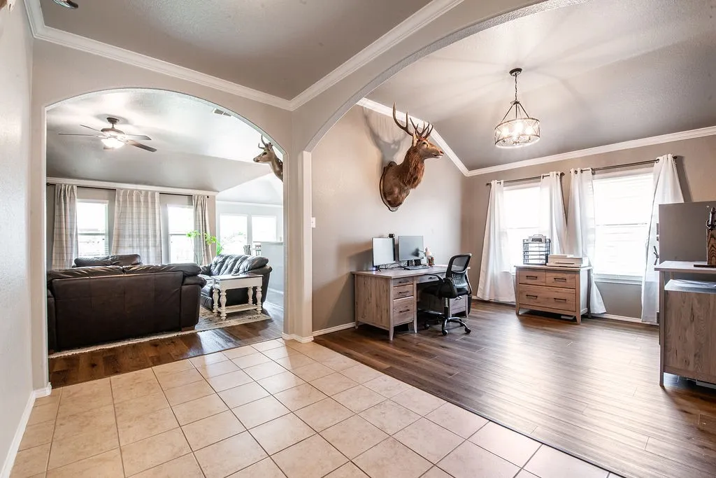 Arched entryway separating rooms featuring tile and wood-finish flooring