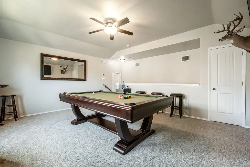 Spacious bonus room featuring vaulted ceilings, a ceiling fan with integrated lighting, neutral wall tones, and light-toned carpeting
