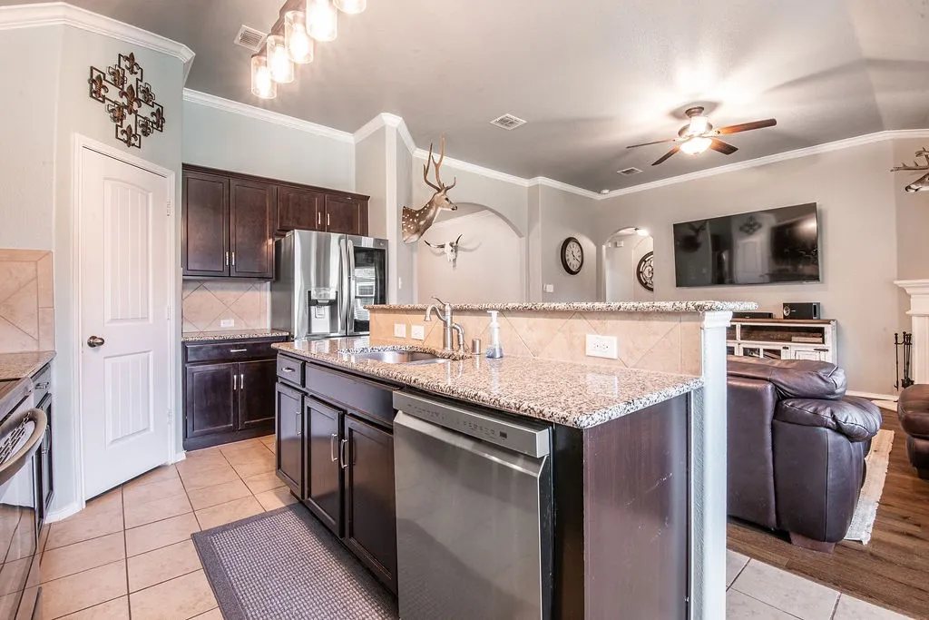 Kitchen island featuring a stainless steel dishwasher, an undermount sink, and granite countertops