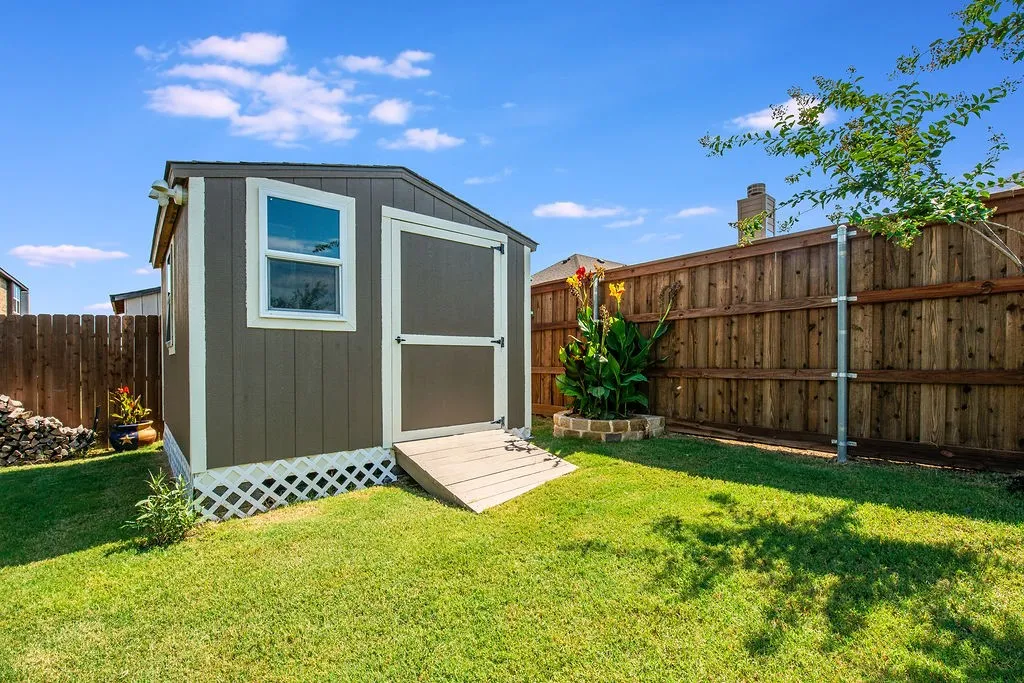 Backyard storage shed featuring a neutral-toned exterior, white trim, and a functional window