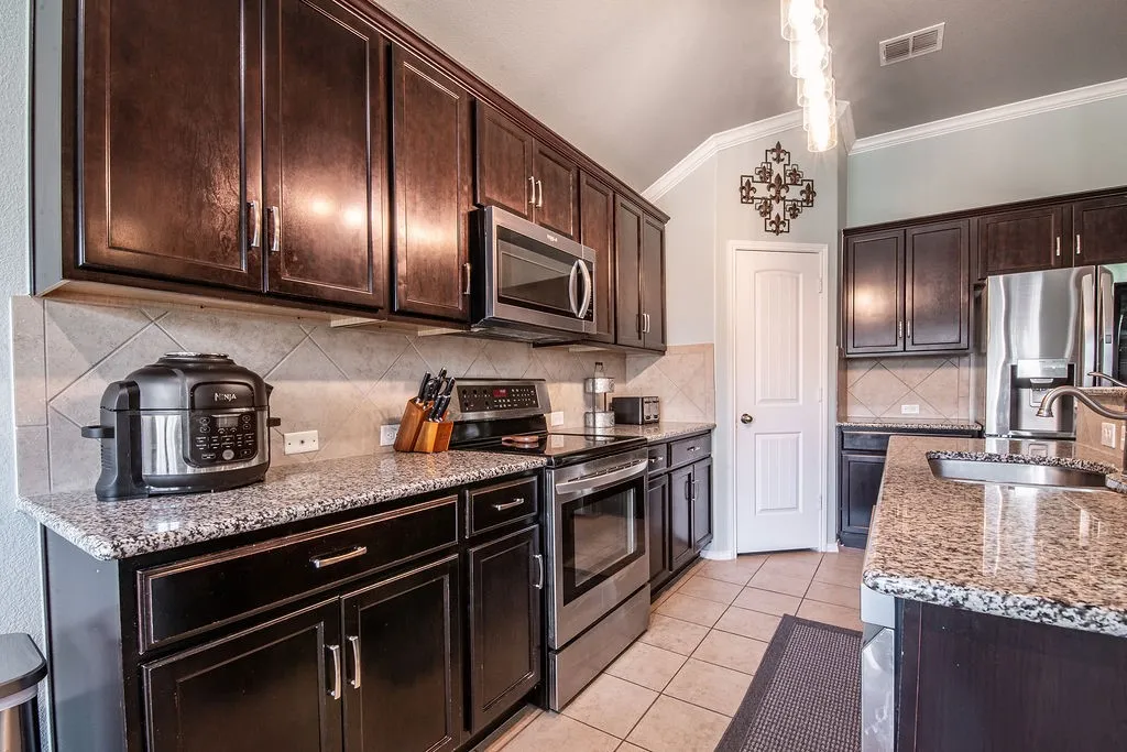 Kitchen featuring dark wood cabinetry, light-toned granite countertops, and stainless steel appliances
