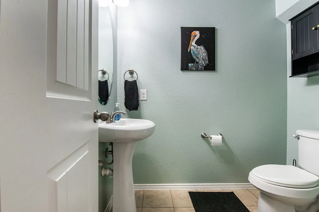 Pedestal sink with chrome faucet, light green walls, and tile flooring