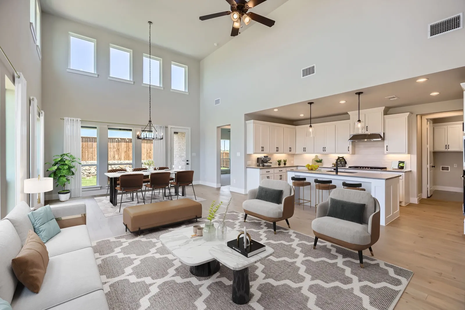 Open-concept living area featuring high ceilings, wood-finish flooring, and a modern kitchen with a large island and pendant lighting