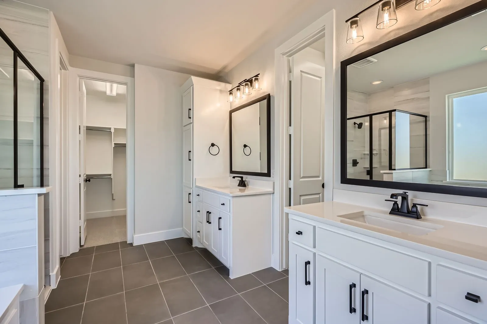 Spacious bathroom featuring dual vanities with quartz countertops, matte black fixtures, and framed mirrors