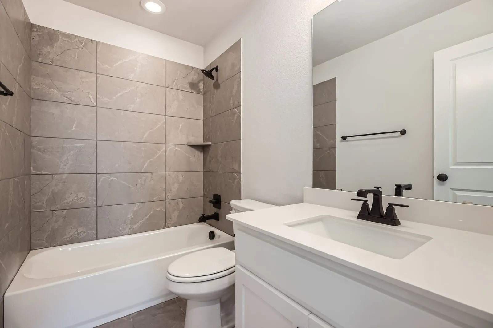 Bathroom featuring a white vanity with an integrated sink, a solid surface countertop, and matte black fixtures