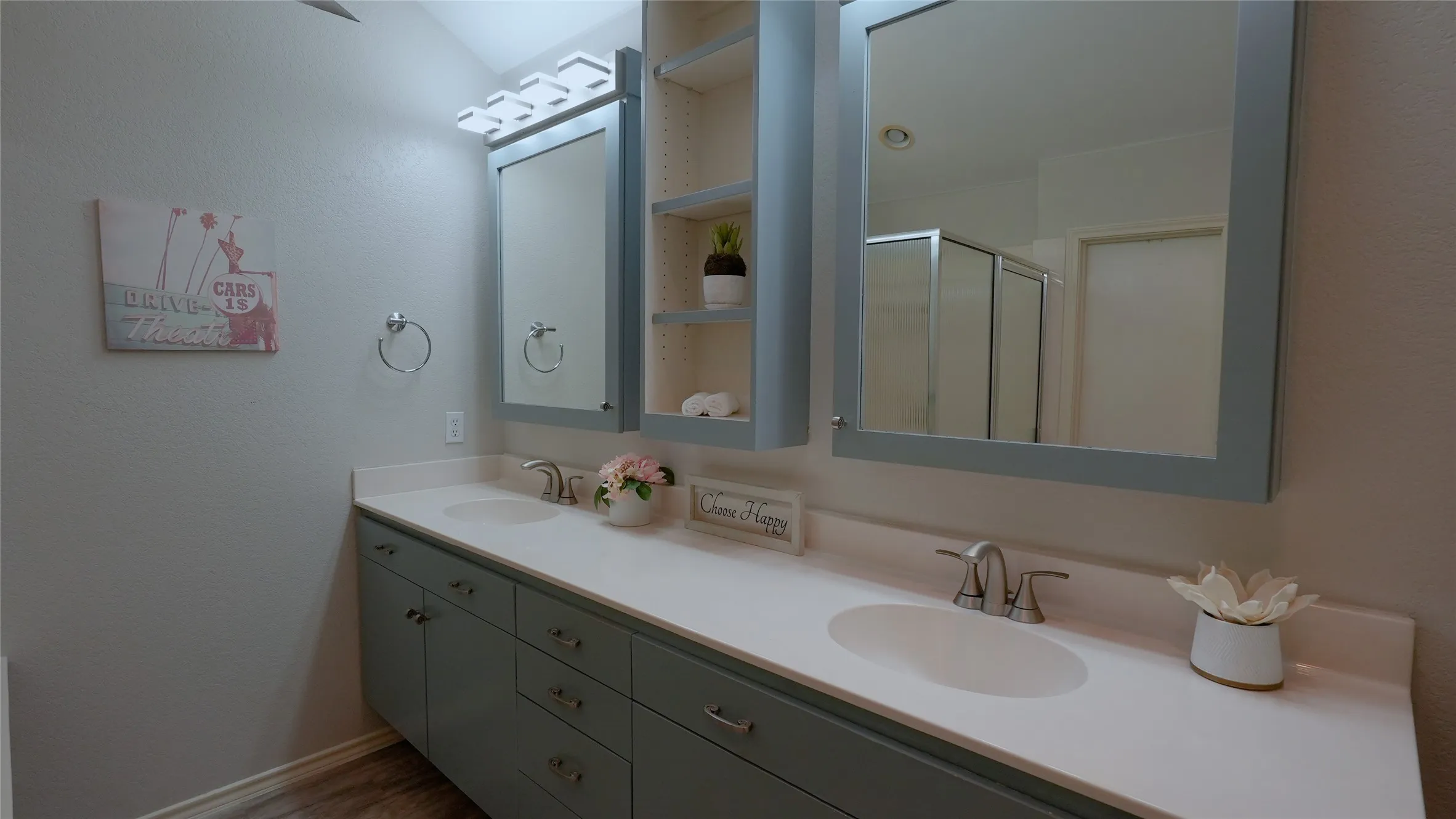 Double vanity with undermount sinks, light-toned countertop, and wood-finish flooring