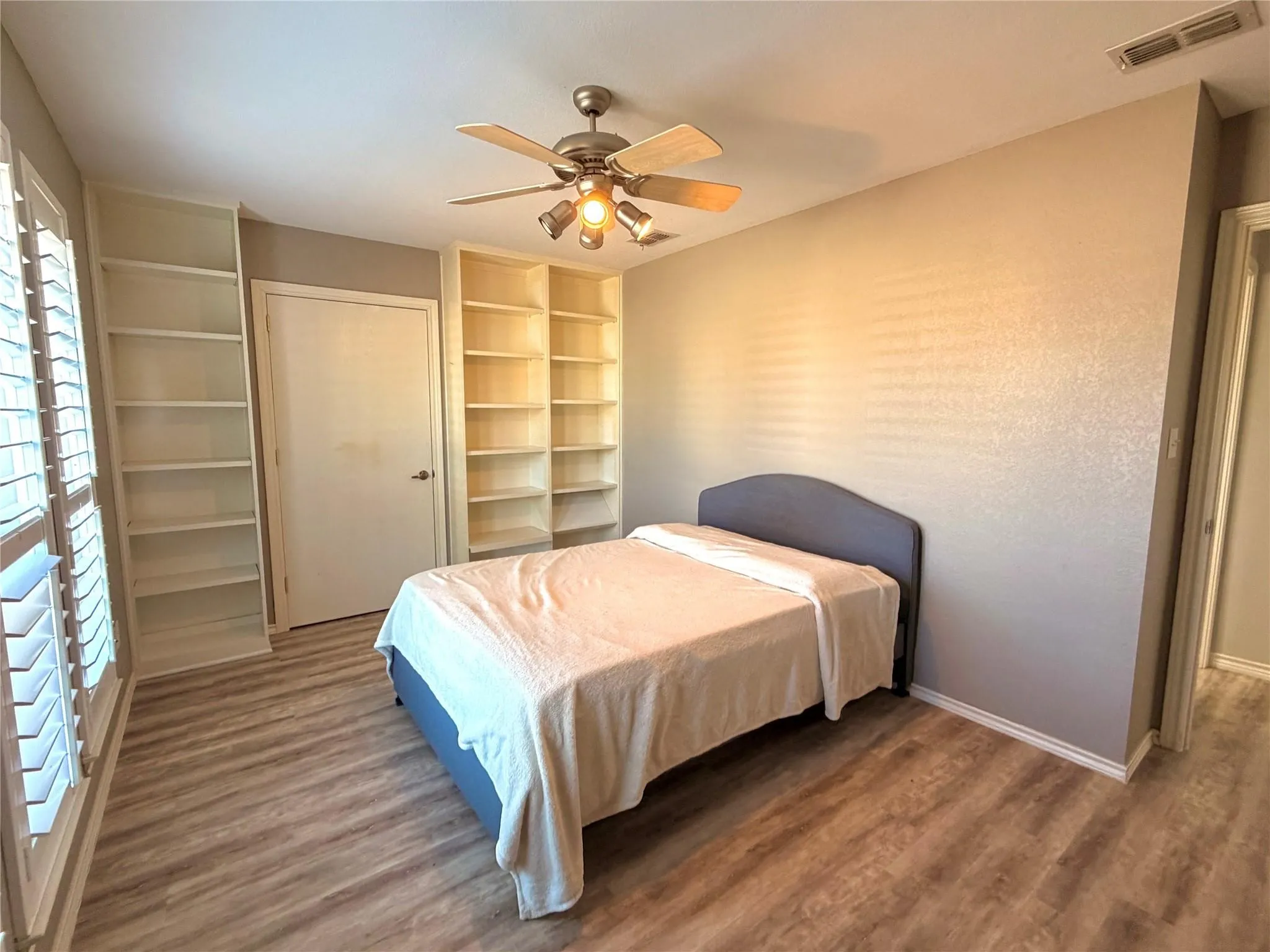 3rd Bedroom, 15x10, featuring plantation shutters, custom built-in shelving, and a spacious walk-in closet.