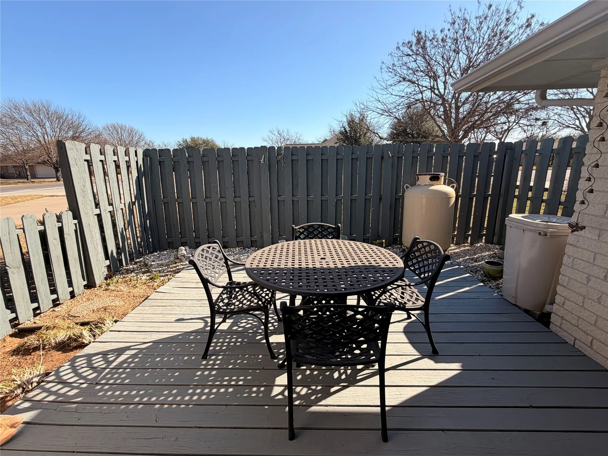 Outdoor patio featuring a grey deck, wood privacy fence, and a gravel border