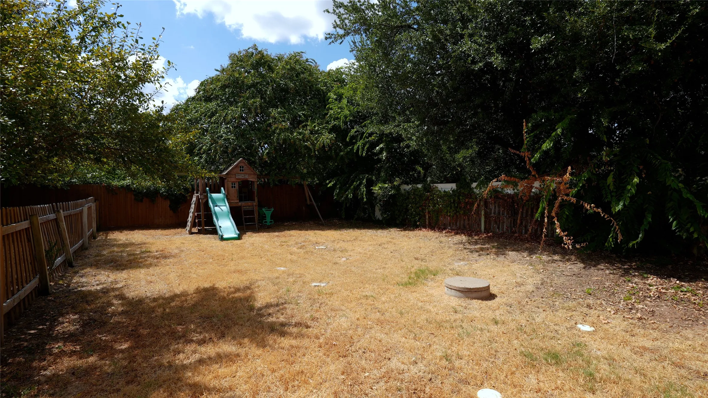 Fenced backyard with mature trees