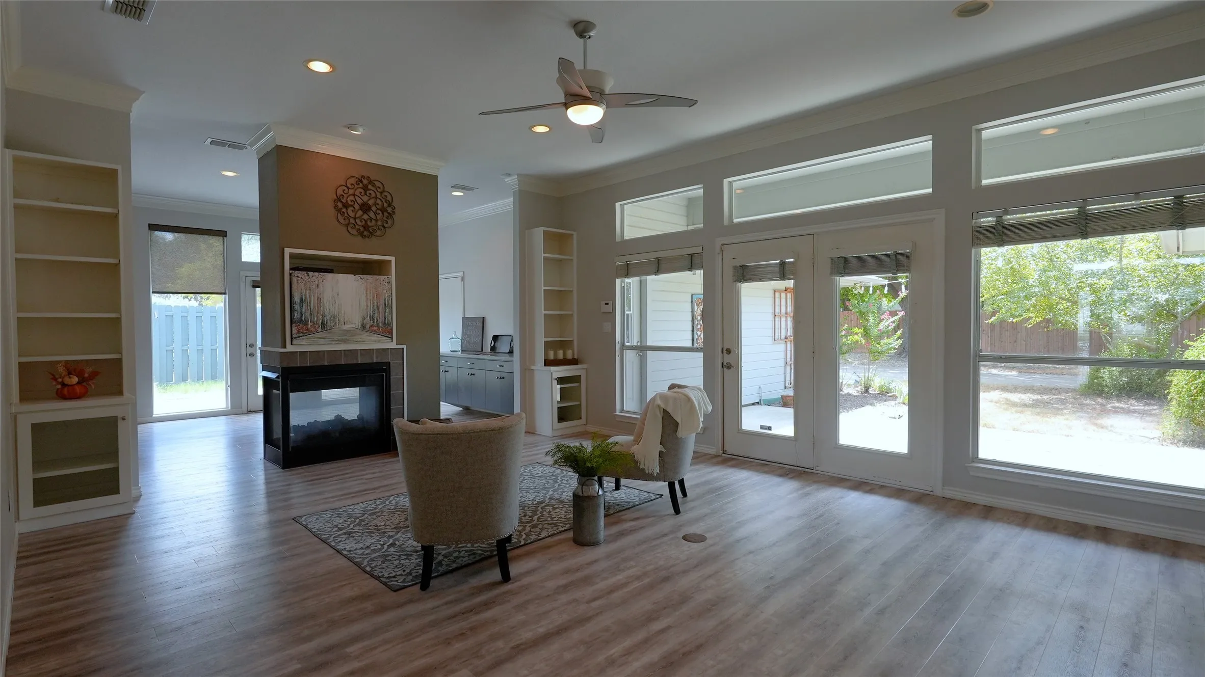 21x16 L Large living room featuring a shared see-through fireplace flanked by two bookcases and large windows that provide abundant natural light.