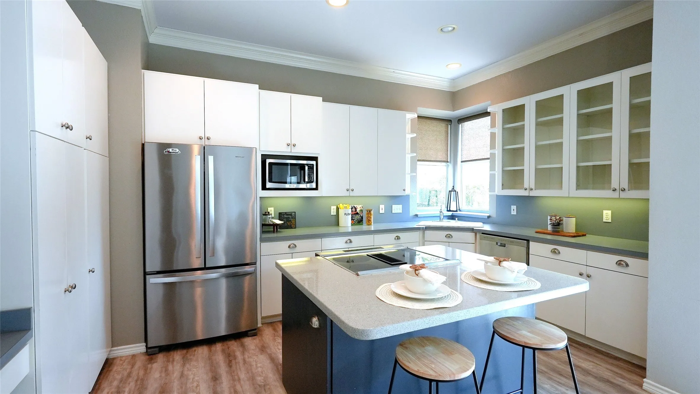 Modern kitchen featuring white cabinetry, stainless steel appliances, a kitchen island with seating, recessed lighting, and wood-finish flooring