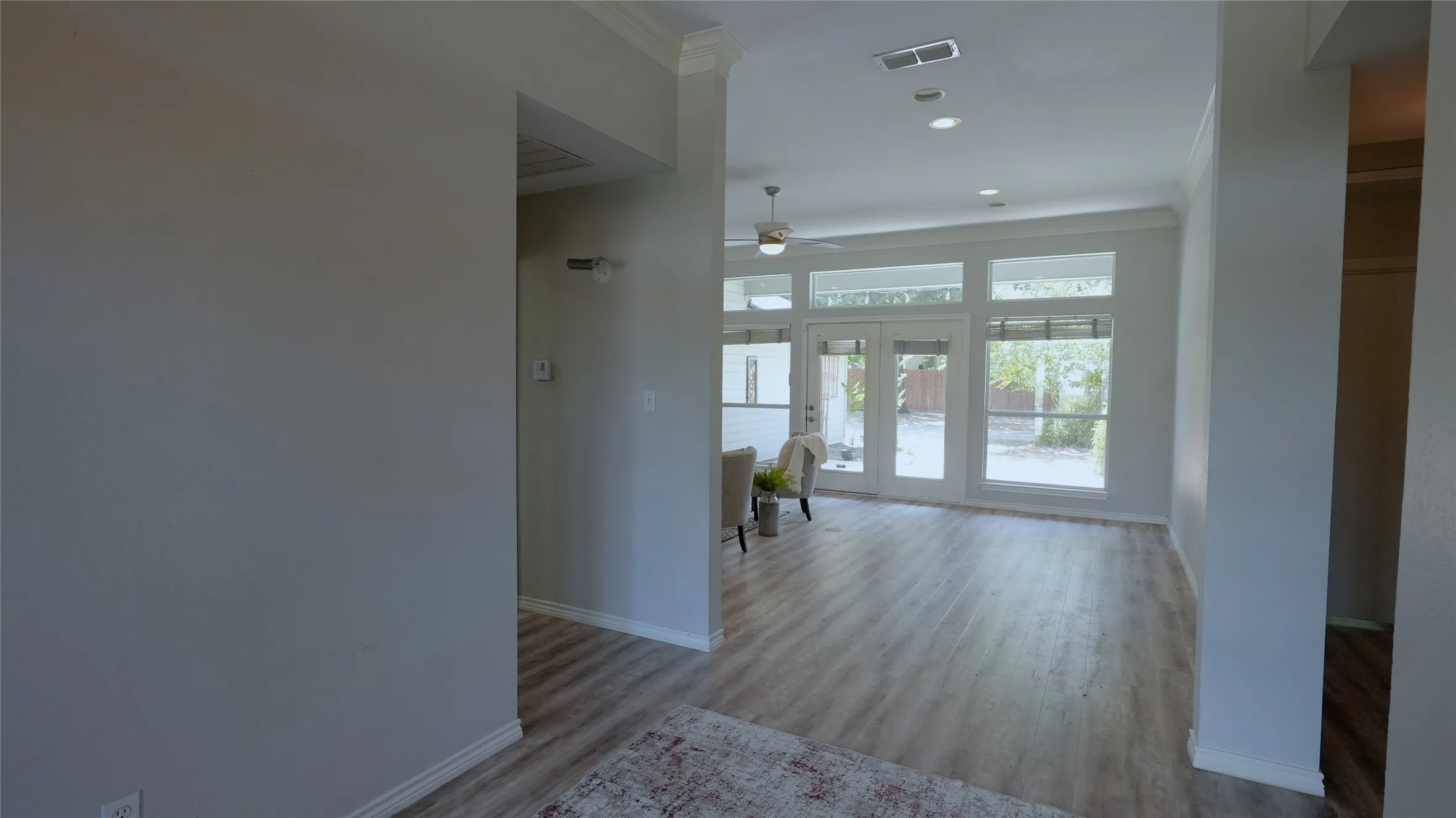 Wood-finish flooring, recessed lighting, ceiling fan, and French doors with transom windows