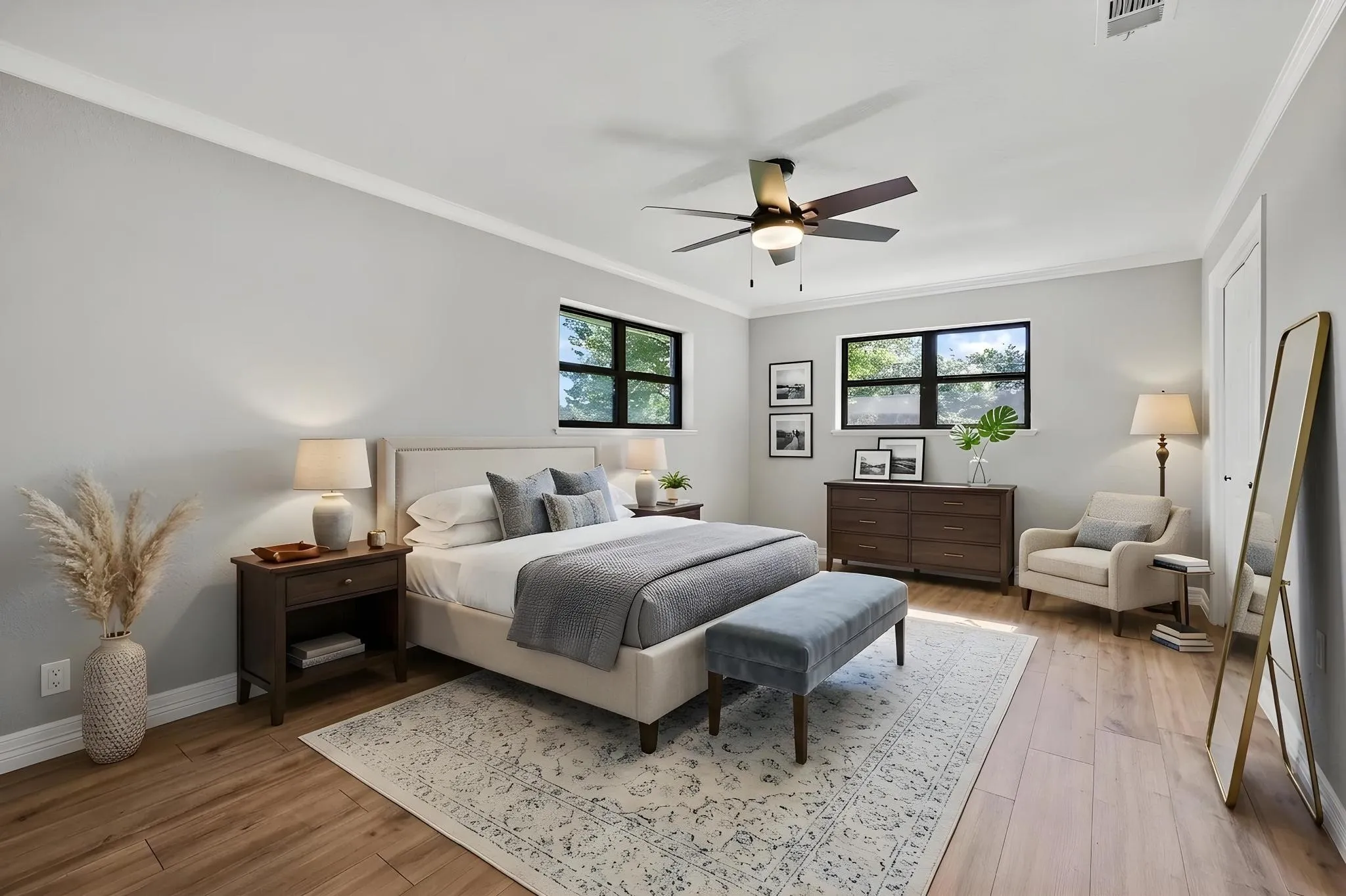 Spacious room featuring wood-finish flooring, two large windows, a ceiling fan, and crown molding