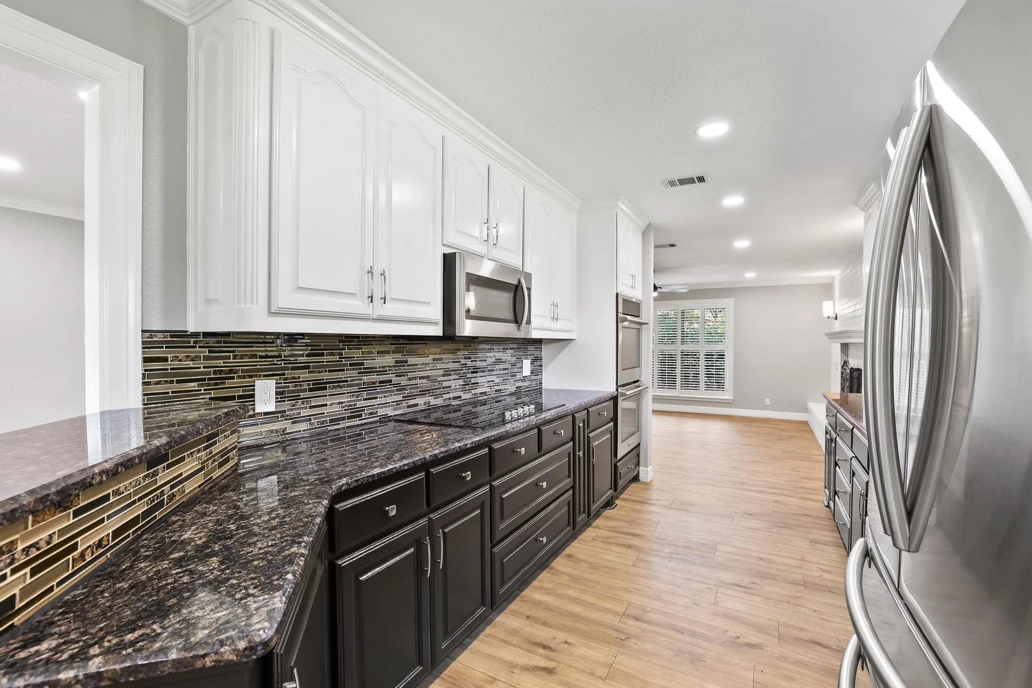 Kitchen featuring dark base cabinetry, white upper cabinetry, and a dark speckled countertop