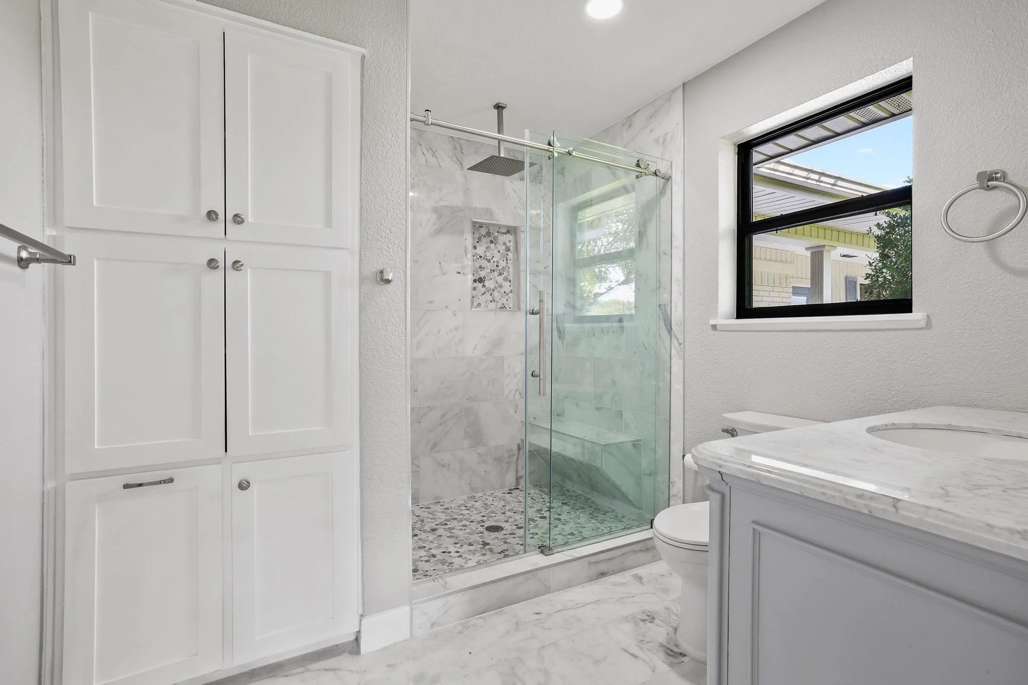 Walk-in shower with clear glass enclosure and built-in bench