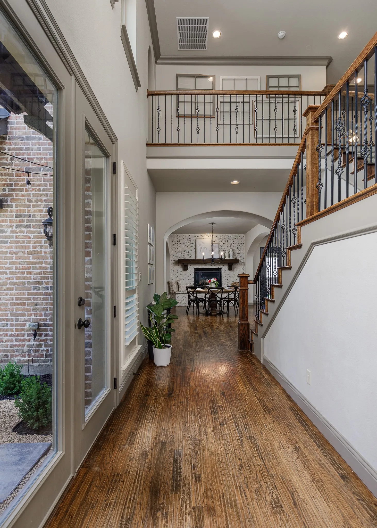 Two-story entry foyer with wood flooring. View down the hall into the dining area.