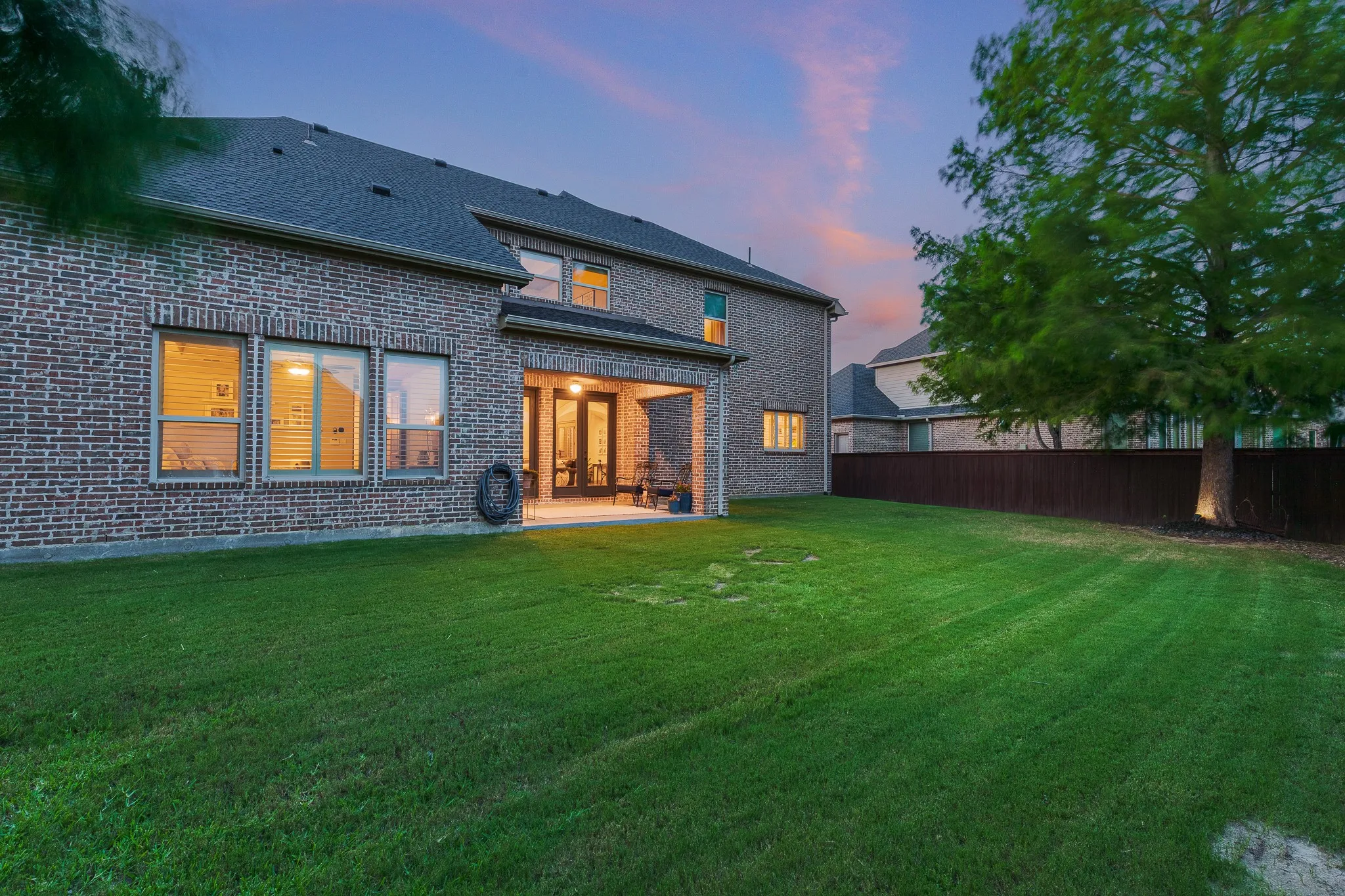 Expansive green lawn with a full brick exterior featuring multiple windows overlooking the yard.
