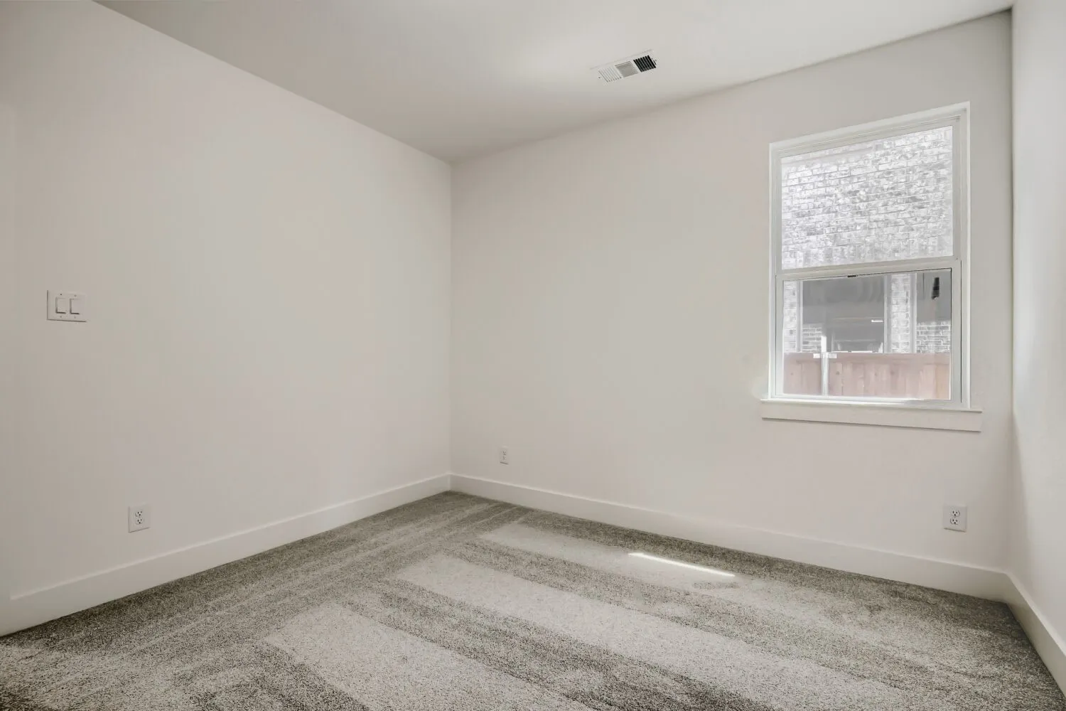 Recessed lighting and a single window with blinds and white trim