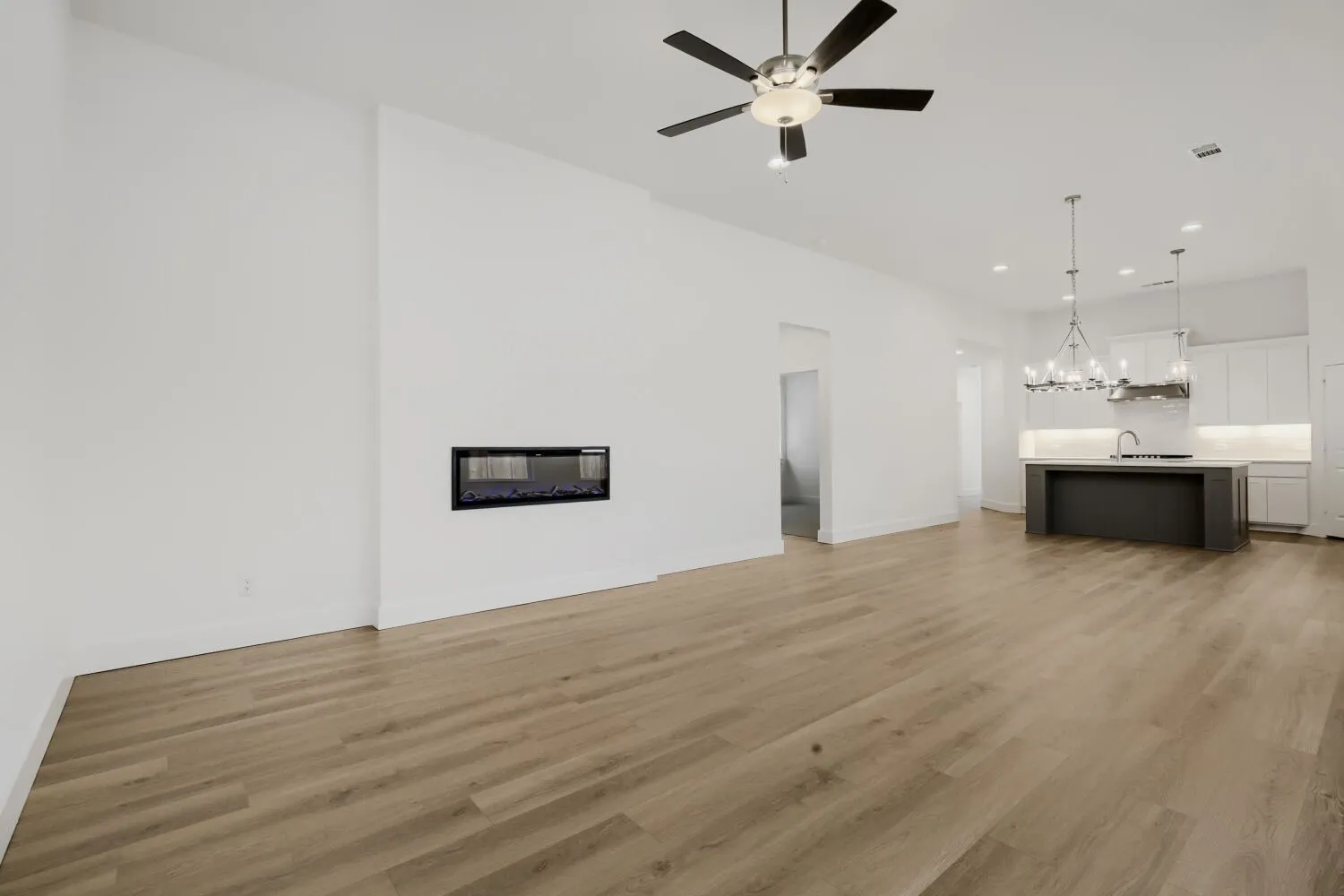 Open-concept living space with wood-finish flooring, a built-in electric fireplace, and a ceiling fan