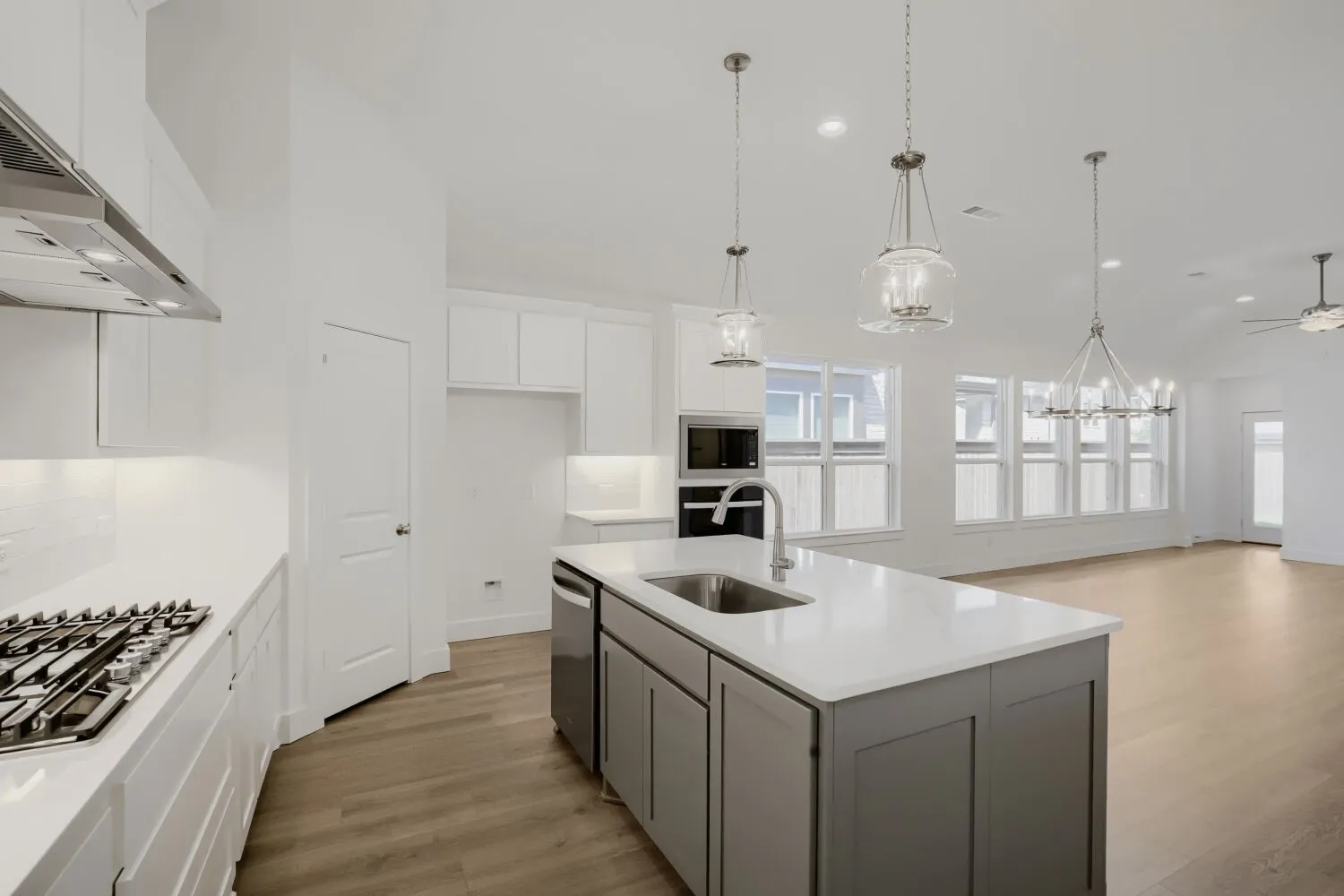 Kitchen featuring white cabinetry, a gas range with a stainless steel vent hood, a kitchen island with a built-in sink, and wood-finish flooring
