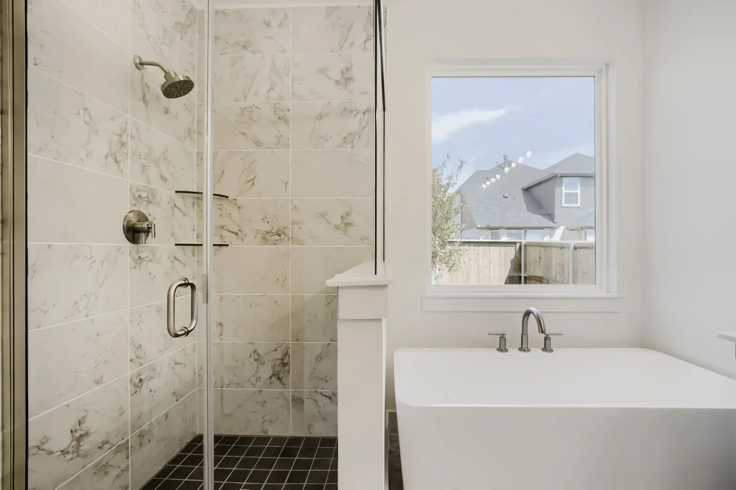 Walk-in shower with clear glass enclosure, marble-patterned tile surround, and brushed nickel fixtures