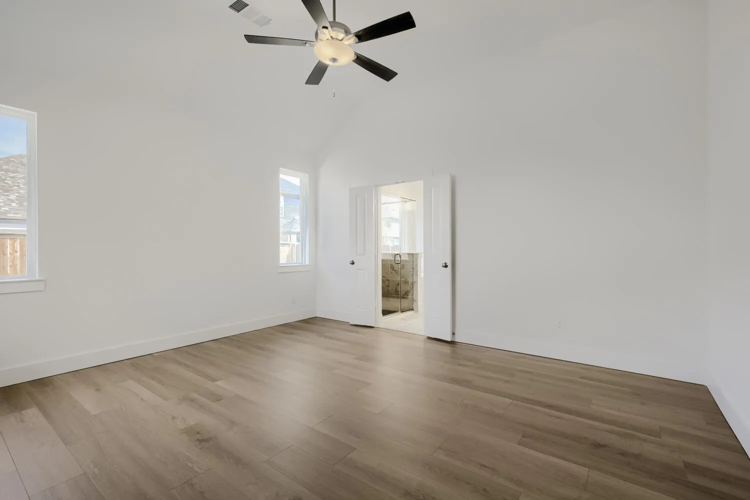 Vaulted ceiling with a ceiling fan, wood-finish flooring, and white walls